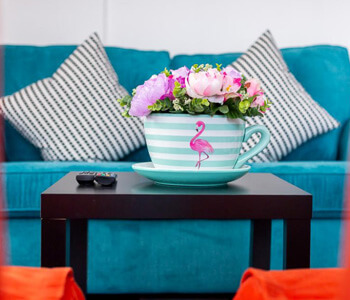 A close up of a tea cup with a pink flamingo and flowers coming out