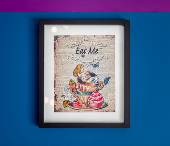 A framed photo with 'Eat Me' on a wall at the Mad Hatter's Tea Room